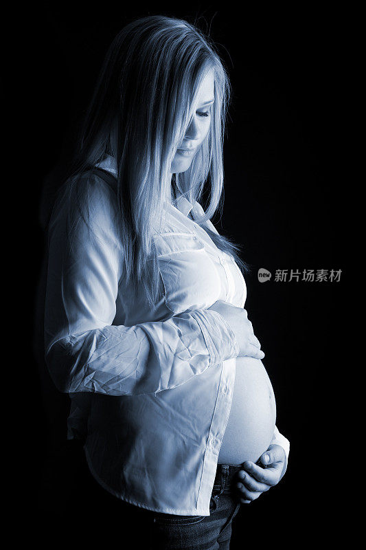 年轻的怀孕女孩抱着她的肚子