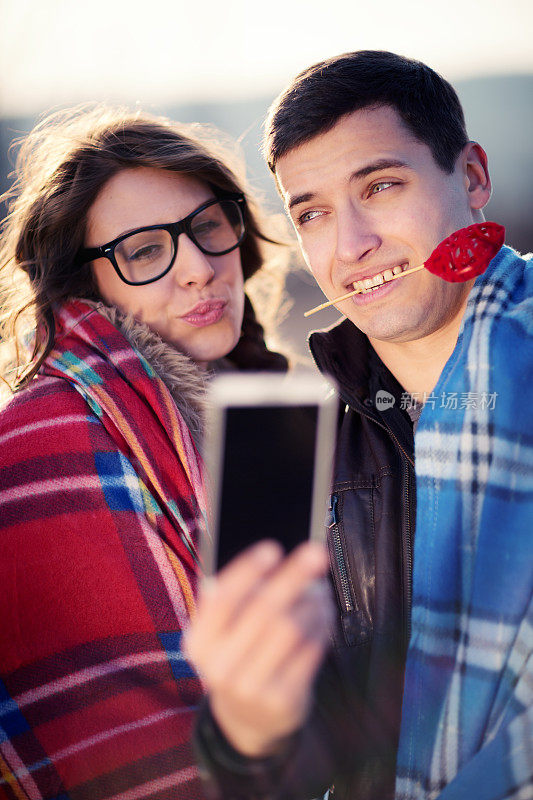 男人和女人在用智能手机拍照