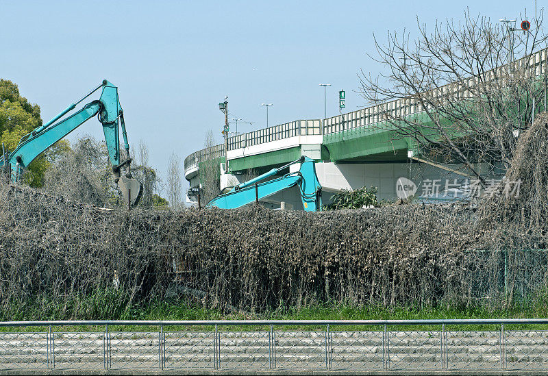 起重机正在清理河流和高速公路之间的土地