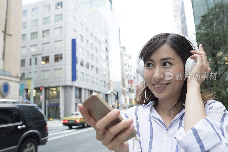 女人在城市里戴着耳机听音乐