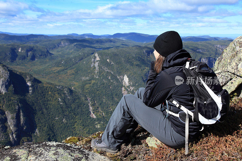 坐在山顶上的女性徒步旅行者