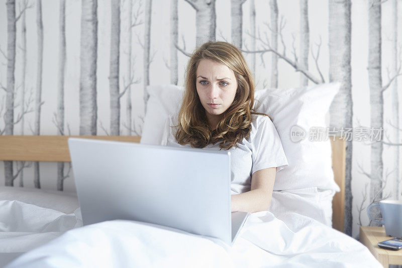 女孩在床上用笔记本电脑