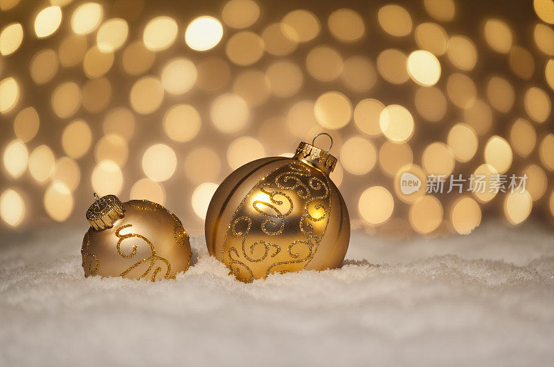 金色的圣诞装饰在雪花里