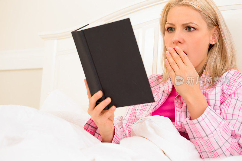 震惊的女人用手捂着嘴看书