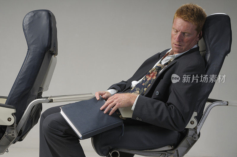 疲惫的商人在飞机上睡觉