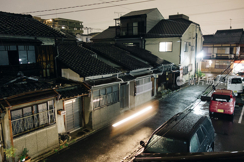 日本京都的住宅街道，夜晚有灯光和大雨