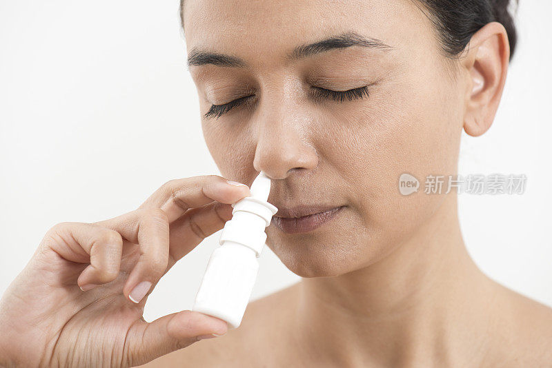 年轻女子喷鼻喷雾鼻孔