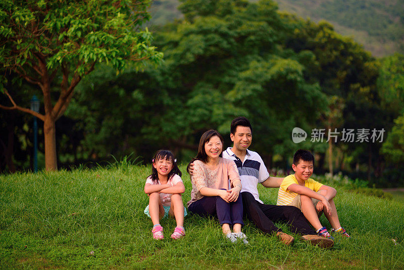 亚洲孩子和父母坐在草地上