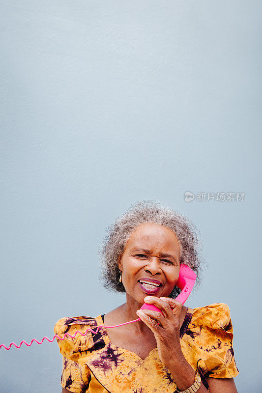 非洲妇女对着镜头微笑，在电话中交谈