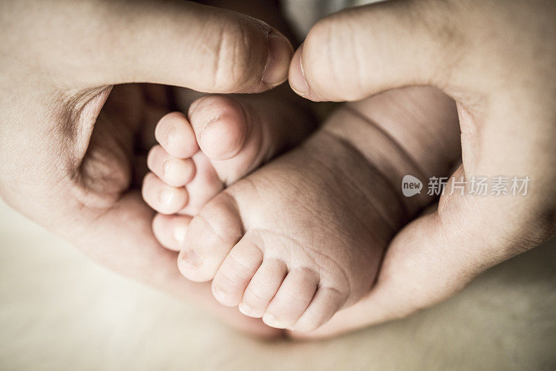 亚洲母亲的手和婴儿的脚