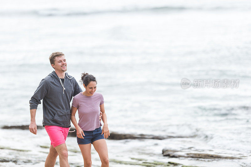一对年轻夫妇在夏威夷美丽的沙滩上散步
