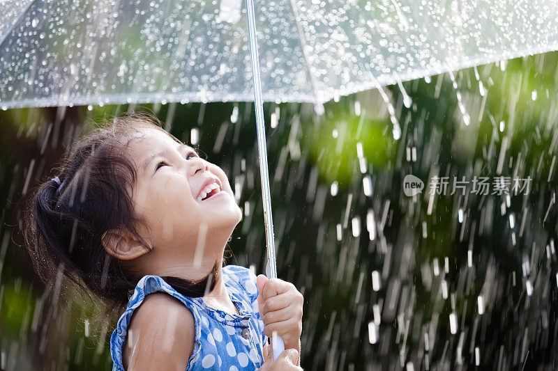 快乐的亚洲小女孩与伞在雨中