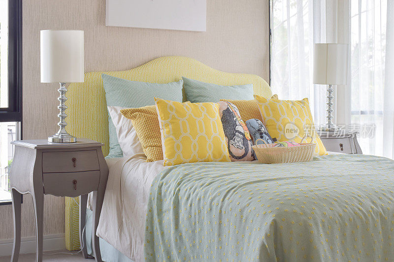 经典风格的床头柜，旁边是台灯，舒适的床上用品，还有许多绿色和黄色的枕头