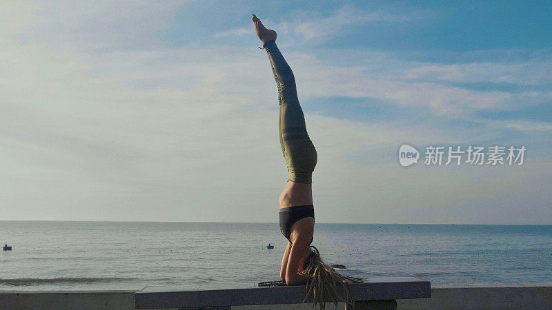 日落时做瑜伽。一个年轻女人在海滩上做瑜伽运动