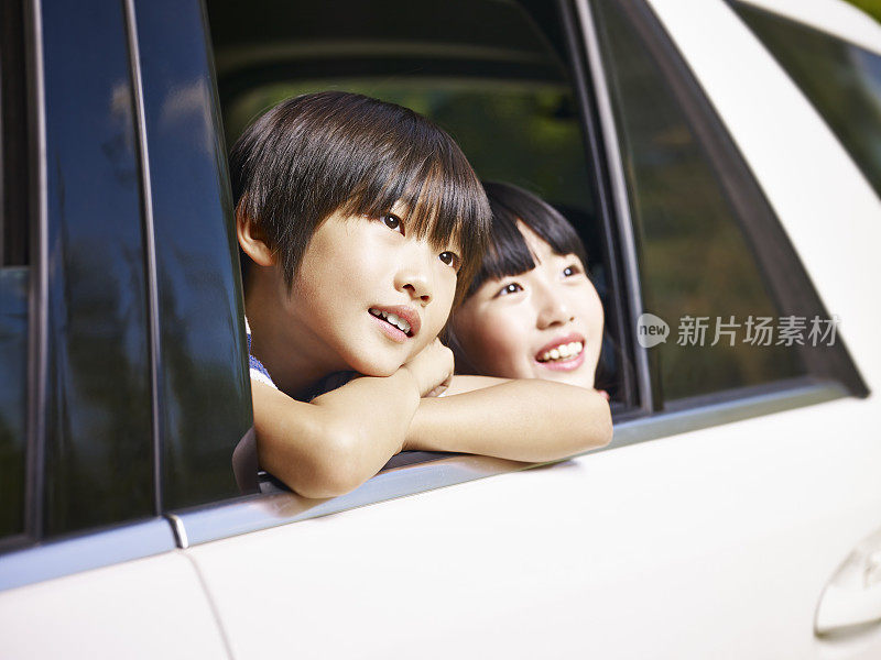 两个亚洲孩子在看风景，而旅行的汽车