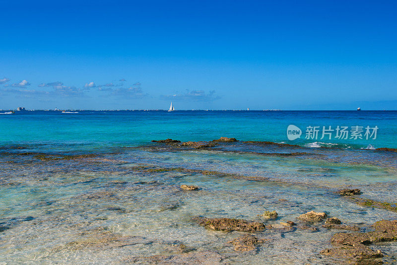 加勒比海海岸与蓝色和蓝绿色的水，帆船和蓝天，坎昆，墨西哥。