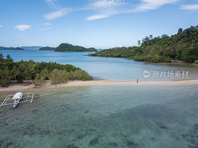 在菲律宾群岛，一名年轻女子在热带海滩上放松双臂，伸开双臂享受自由。人们旅行豪华度假目的地的概念