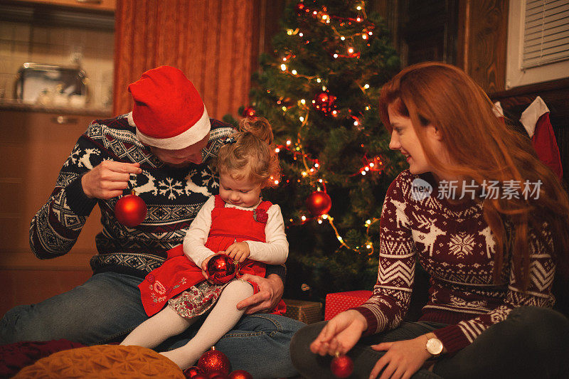 年轻的家庭和小女孩装饰圣诞树