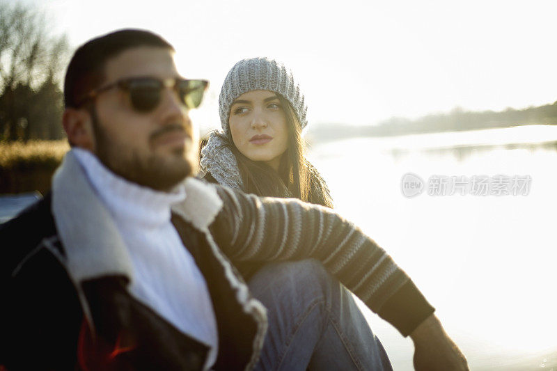 一对美丽的夫妇坐在湖边的公园里，坐在码头上