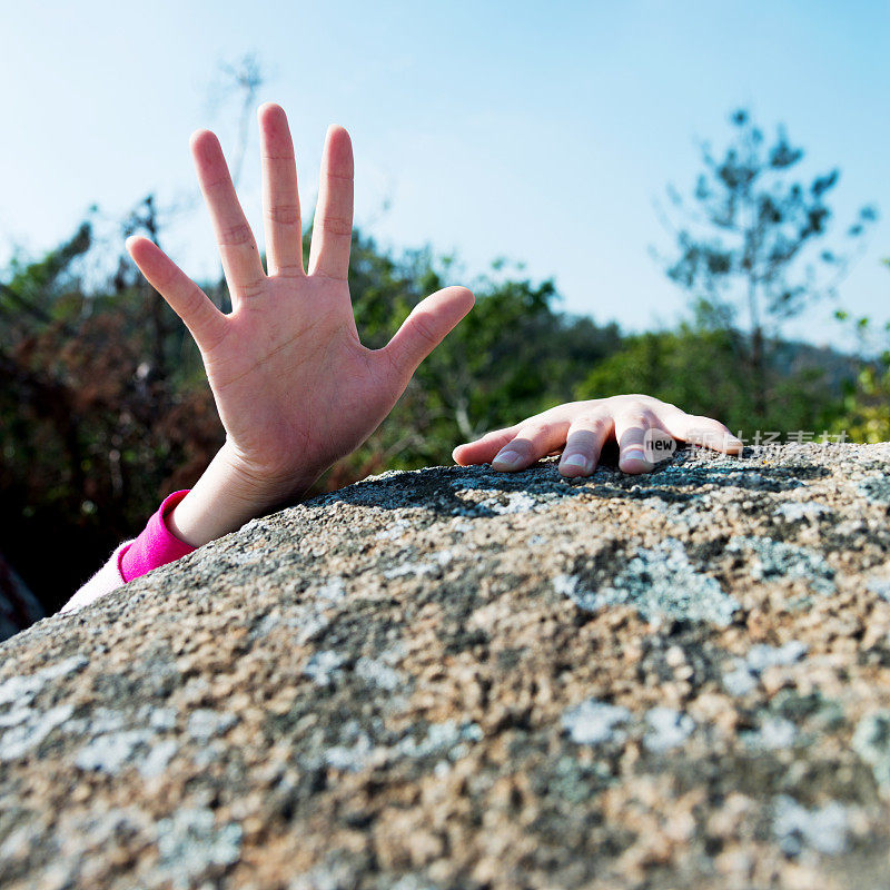 女人伸手在岩石上求助