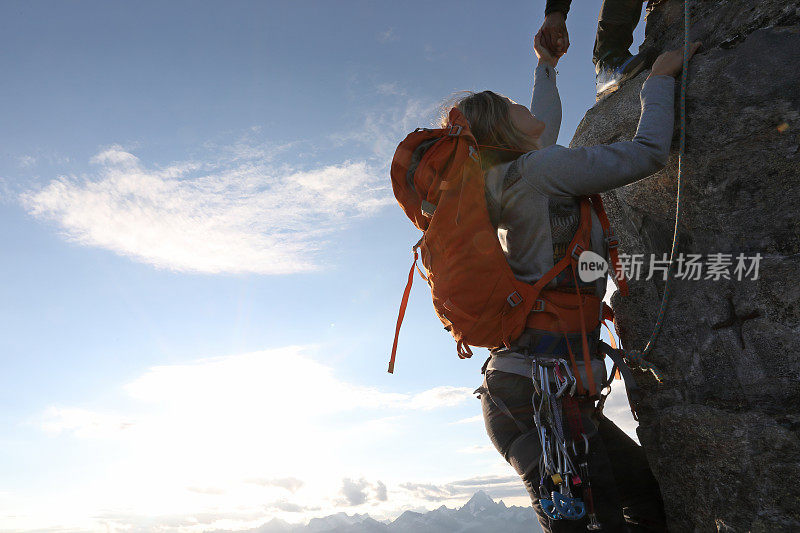 登山者在崖壁上伸出援手