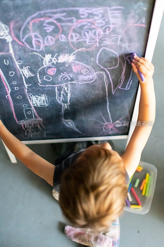一个三岁的小男孩在黑板上画画