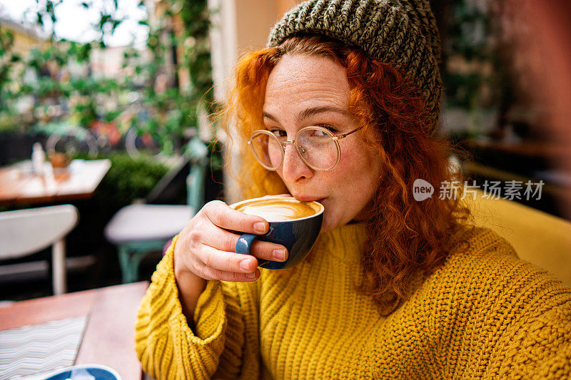 年轻的成年女性一边喝咖啡一边自拍