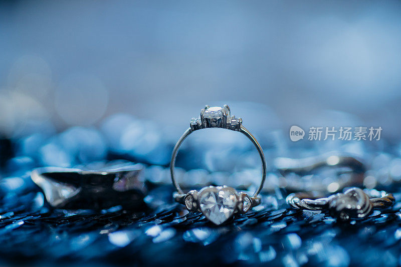 近婚钻石戒指在深蓝色的背景与散景
