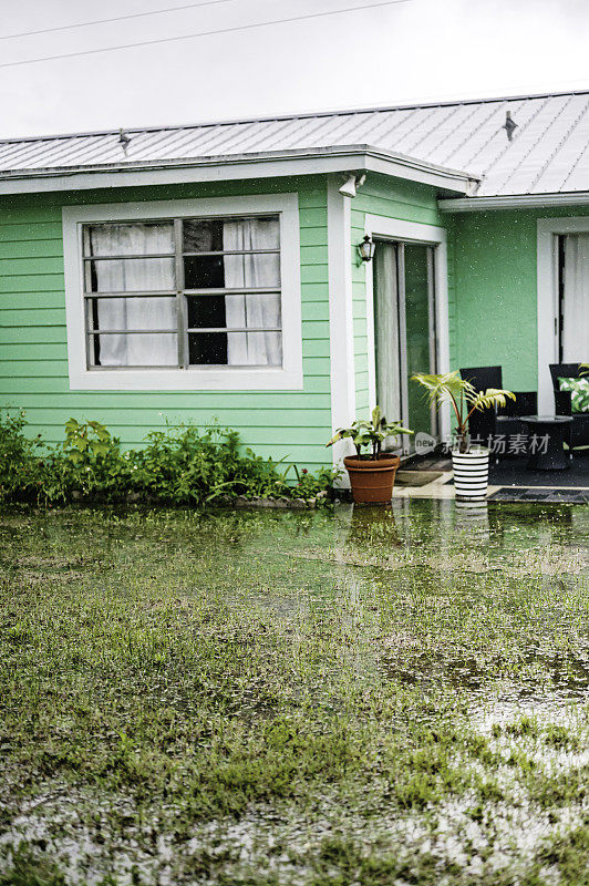 暴雨袭击了一个独栋房屋的屋顶，屋顶上有排水沟，热带风暴淹没了院子