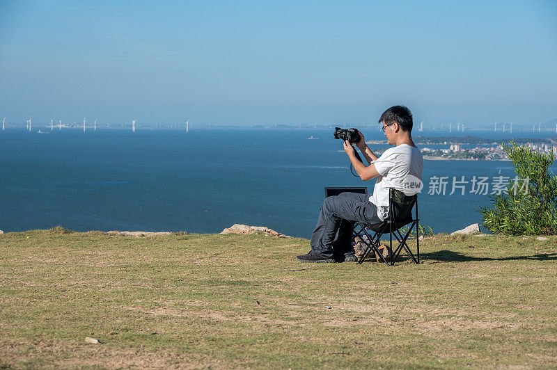 一个亚洲人正在度假，在野外的海边拍照