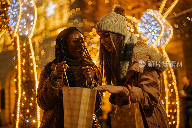 两个兴奋的女性朋友拿着圣诞礼物