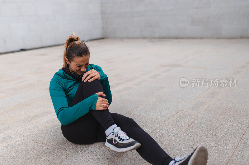 年轻的女运动员在户外锻炼时膝盖受伤