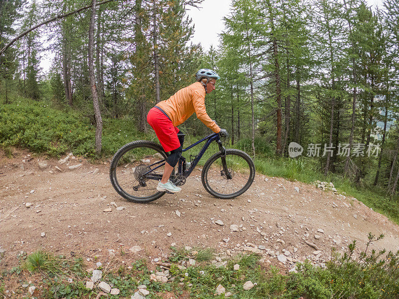 年轻女子骑山地车沿着小径在夏天