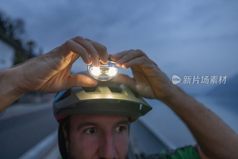 骑自行车的人调整头盔上的头灯，夜间户外健身
