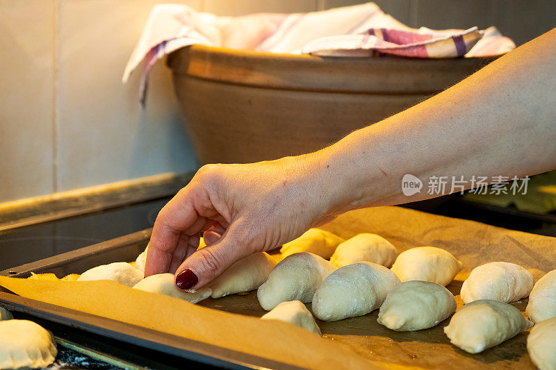 一个女人的手把小的生馅饼放在平底锅里。肉馅饼是拉脱维亚传统的节日菜肴。