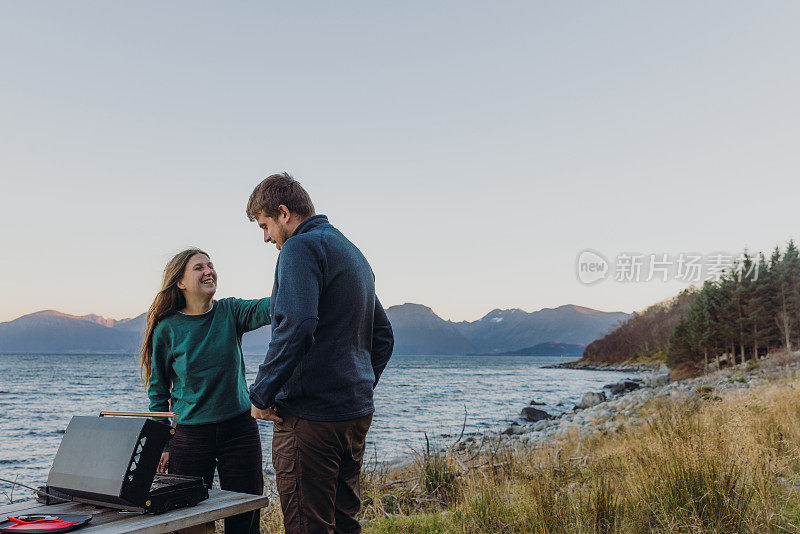 一个女人和一个男人在海边野餐，凝视着快乐的日落时分