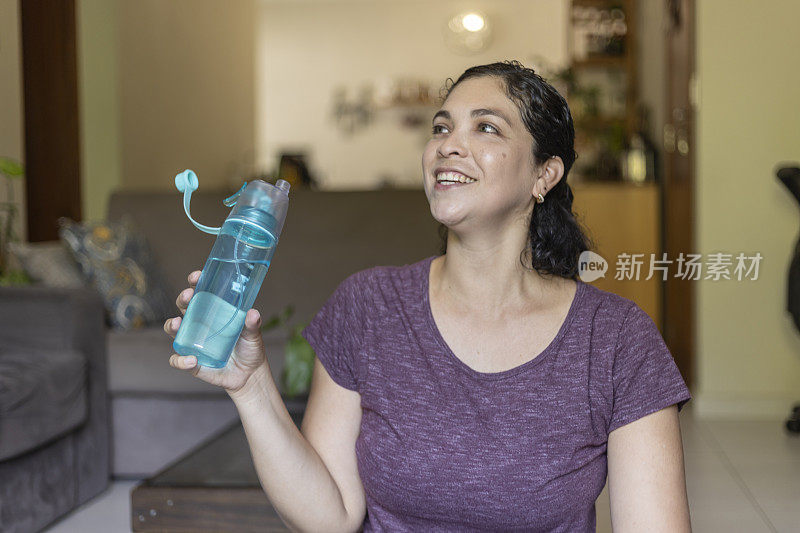 一名拉丁妇女在瑜伽运动后用瓶子喝水