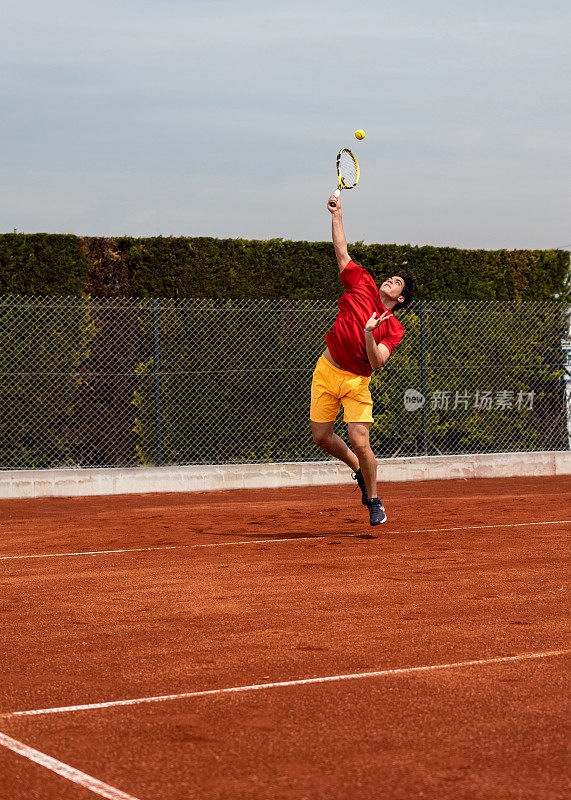 男子网球运动员还在红土球场打垂直网球