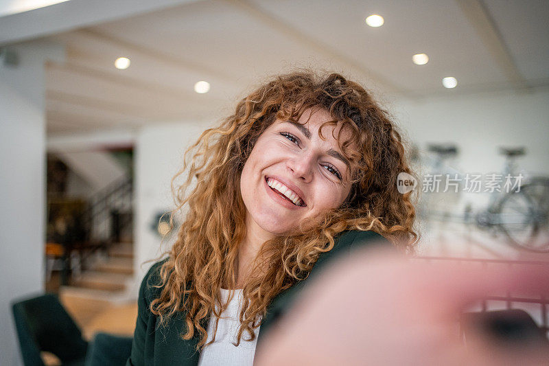 漂亮的卷发女孩站在自助餐厅自拍，穿着绿色运动夹克，休闲优雅