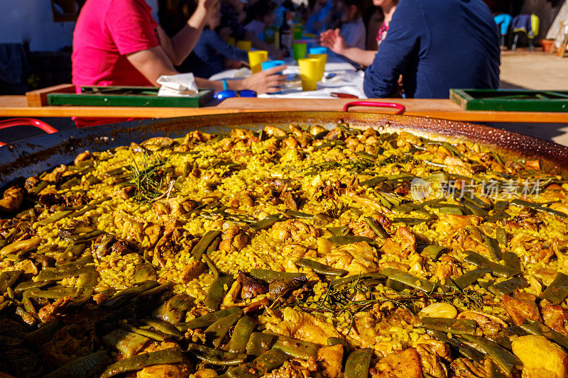 黄色的米饭配上肉和蔬菜，瓦伦西亚海鲜饭，典型的西班牙美食。