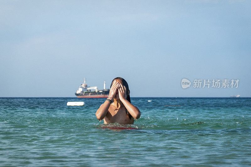 他用手在海里泼水。一个夏天的早晨。忒涅多斯岛。爱琴海北部，12岁的帅哥。长头发的