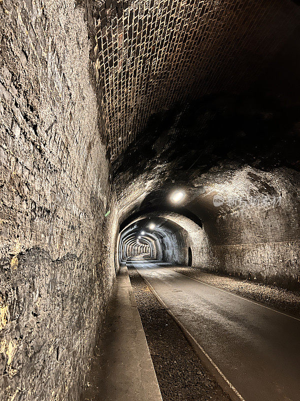 步行穿过维多利亚时代的火车隧道，看到拐角处的景色。
