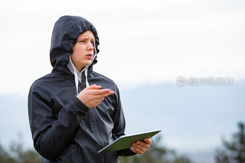 十几岁的男孩探险家寻求方向与数字平板电脑户外