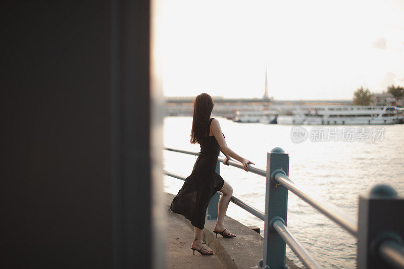 身穿黑色连衣裙的年轻美女在伊斯坦布尔的加拉塔桥上欣赏日落