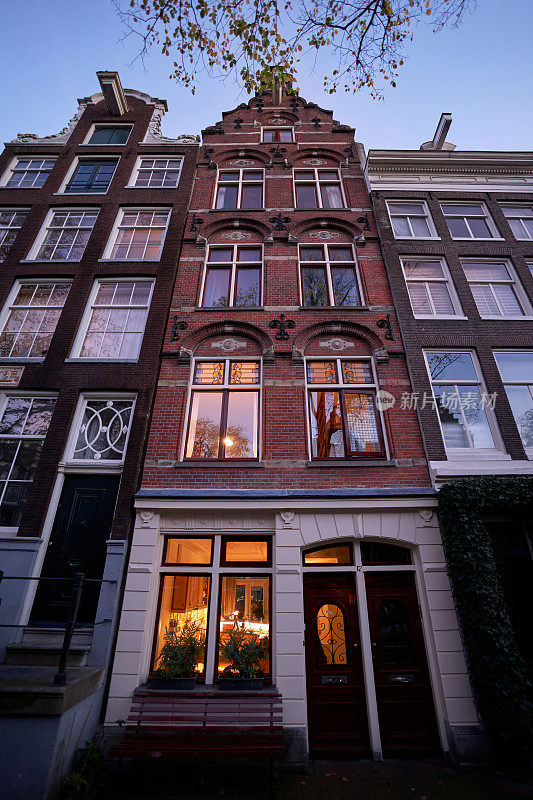 黄昏时阿姆斯特丹狭窄高大的运河房屋的正面景观