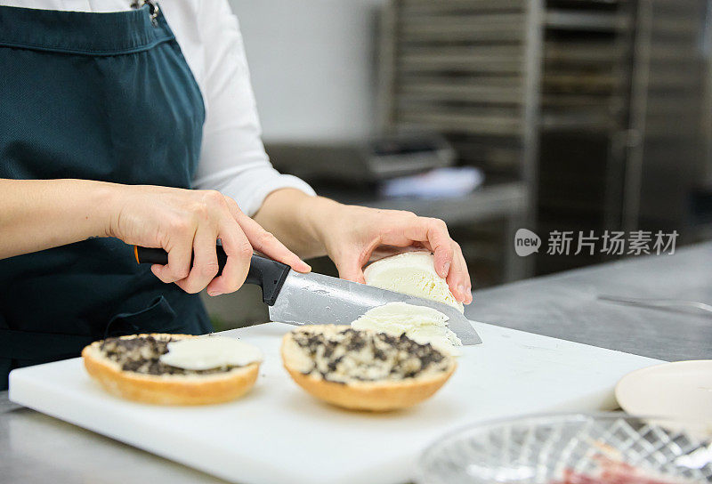 一个无法辨认的女厨师在面包店的厨房里切马苏里拉奶酪准备美味的松露三明治的特写镜头。