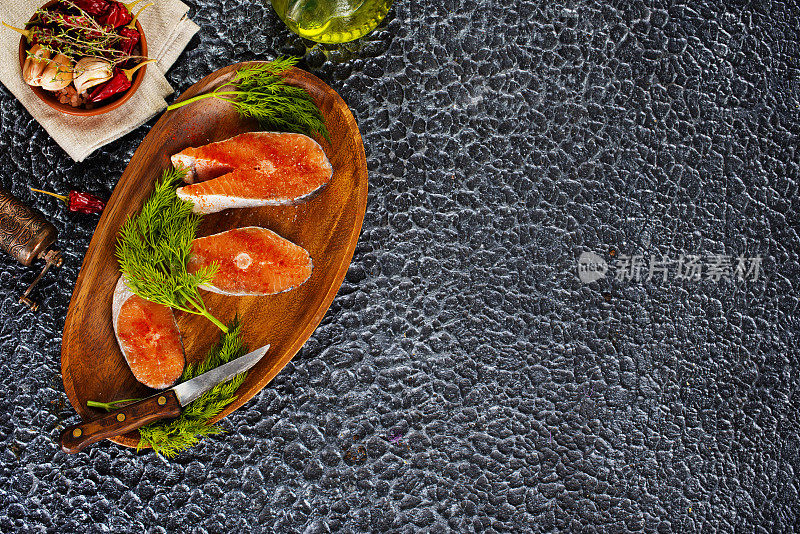 新鲜鲑鱼排准备烹饪的生鱼。黑色石板桌的俯视图。