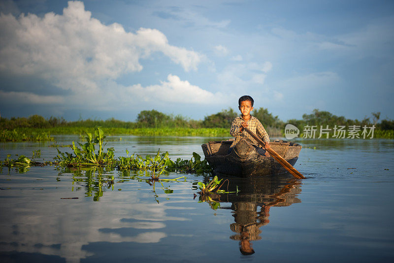 柬埔寨男孩在他的漂浮村庄乘船旅行。
