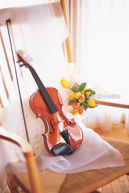 一束黄色和橙色的花和一把小提琴在椅子上