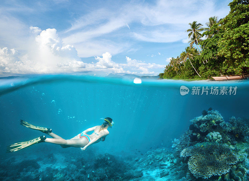 女人浮潜在热带水域附近的异国情调的岛屿